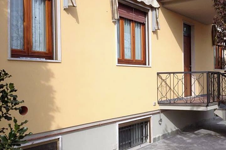 Facciata di una casa tinteggiata di giallo chiaro, con finestre, zoccolatura e balcone in ferro battuto