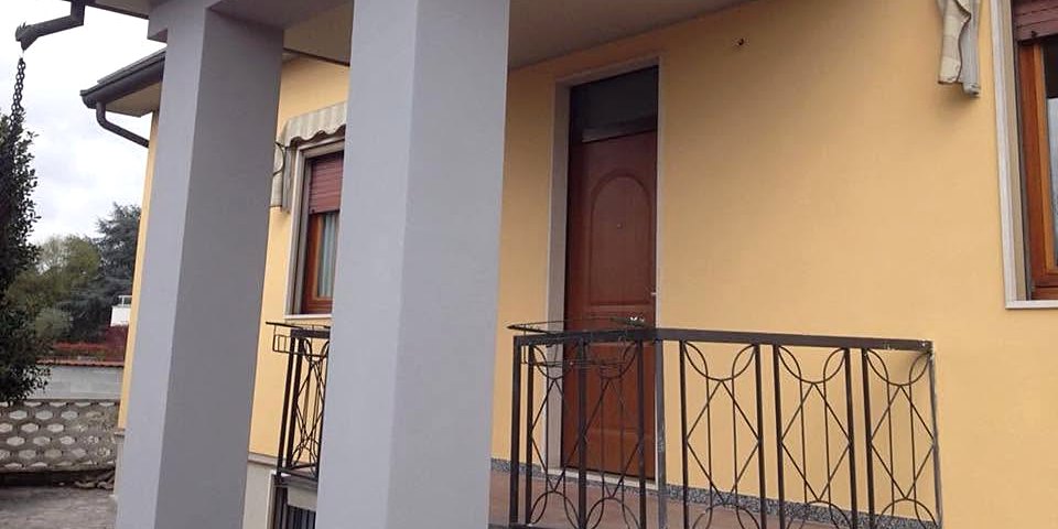 Portico di una villetta con facciata gialla e pilastri dipinti di grigio