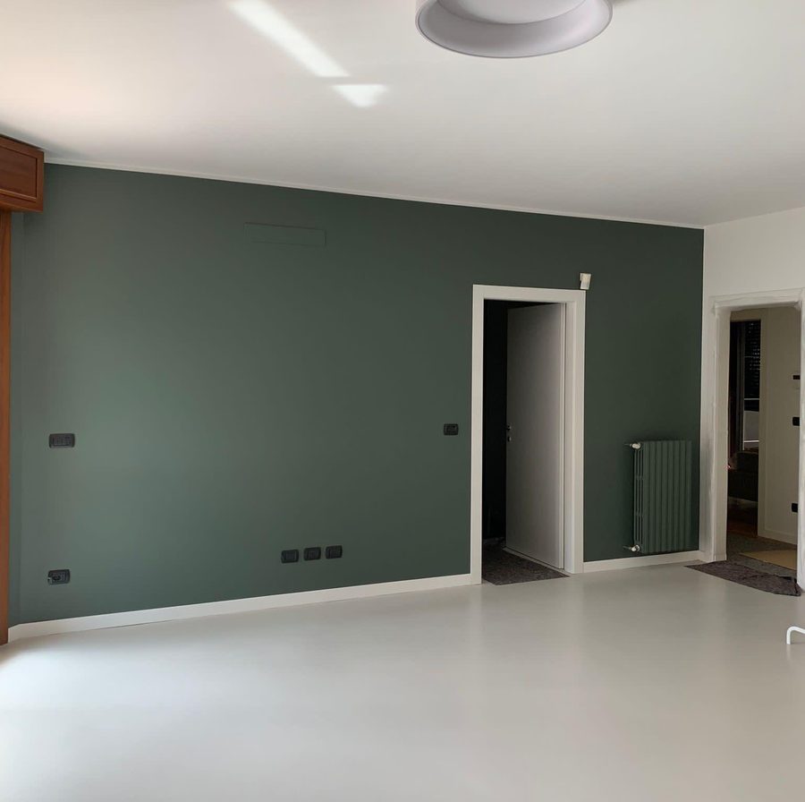 Soggiorno con parete verde e termosifone dipinto dello stesso colore